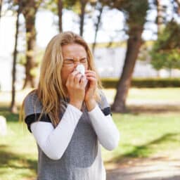 Woman blowing her nose in the park