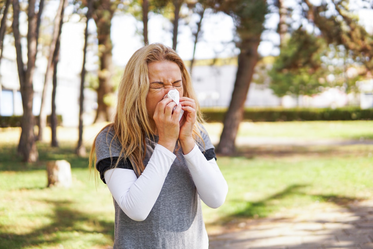 Woman blowing her nose in the park