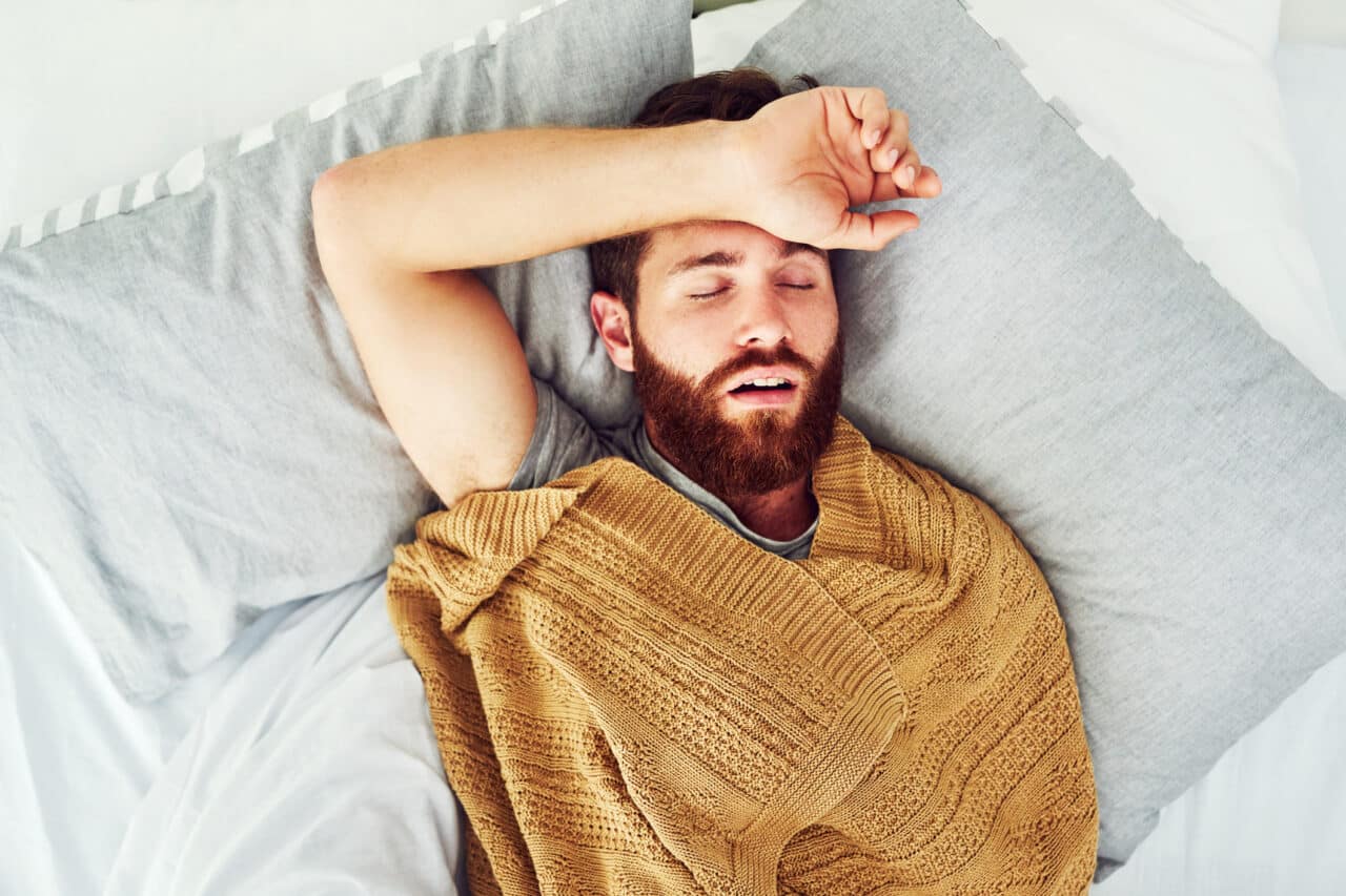 Young man snoring in bed.