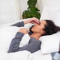 Woman in bed holding her sinuses