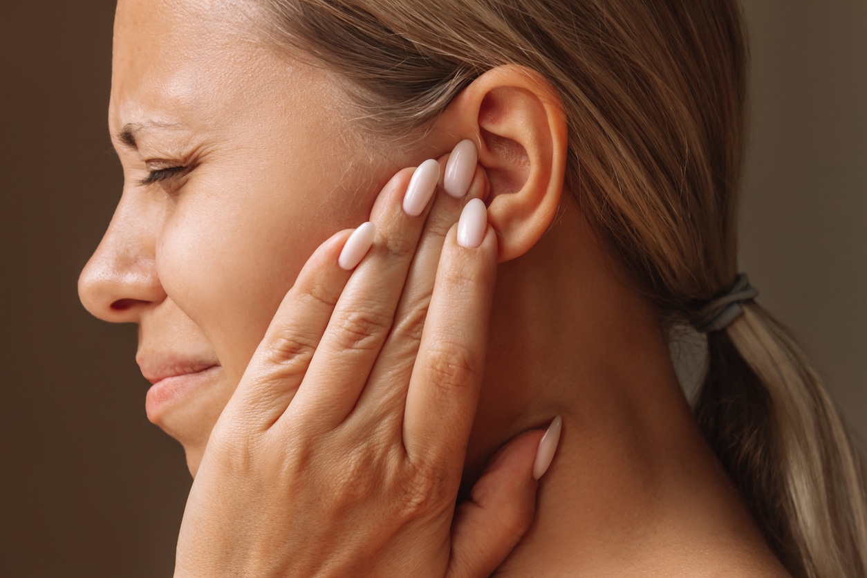 Woman holds ear in pain