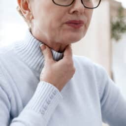 Woman holding her throat having trouble swallowing
