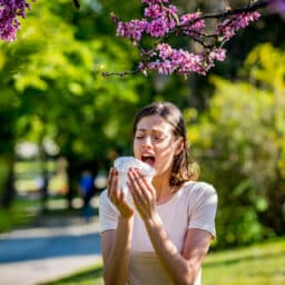 Woman sneezes into tissue in park