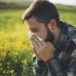 Man with allergies sneezes outside