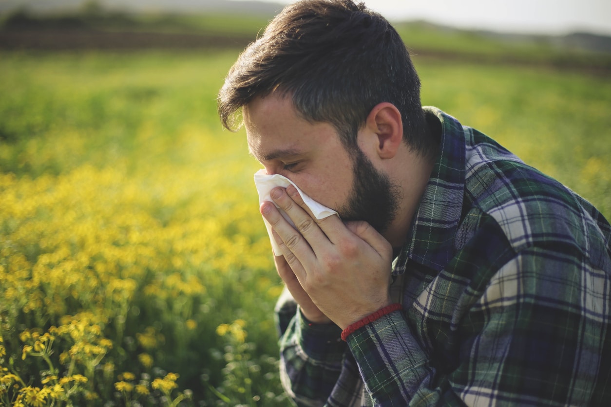 Man with allergies sneezes outside