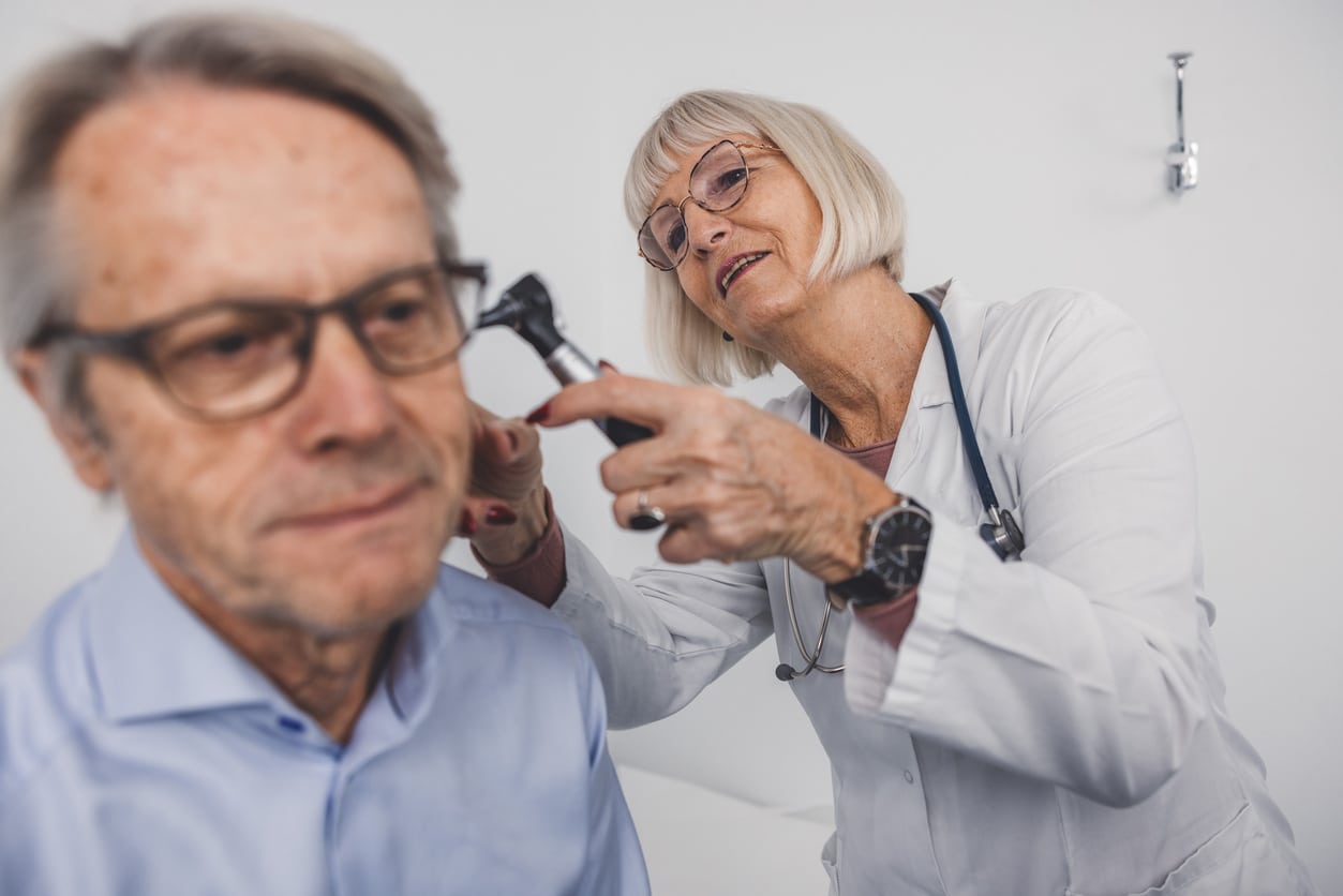 Audiologist examining patient's ear with otoscope